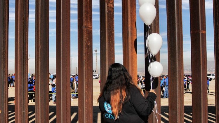 A woman stands at the border between the United States and Mexico. From January 7-13, the U.S. Bishops observe National Migration Week, celebrating the immigrant nature of America.