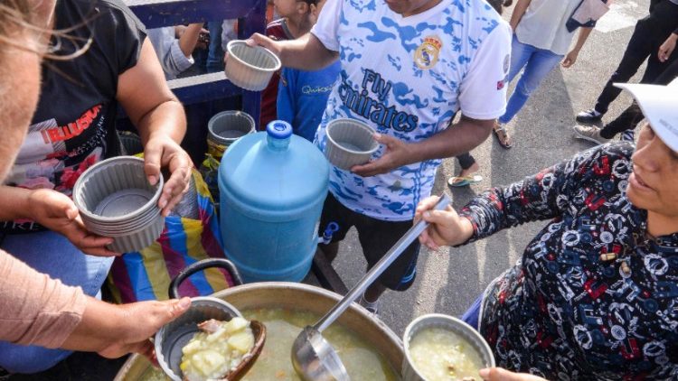 Venezuelan nationals receive food from religious volunteers in Tumbes at the border with Ecuador while they wait for authorisation to enter Peru.
