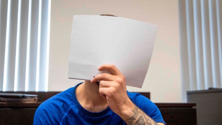 Ali Bashar covers his face in front of the cameras upon entering the courtroom