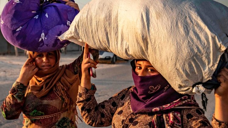 Civilians carry their belongings as they flee amid Turkish bombardments on Syria's northeastern town of Ras-al-Ain 