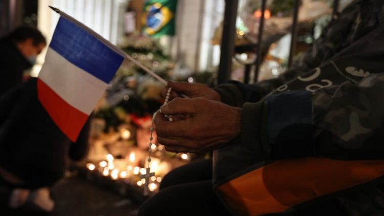 Une personne prie avec un chapelet et un drapeau français devant la basilique Notre-Dame de l'Assomption, à Nice, au surlendemain de l'attentat du 29 octobre 2020.