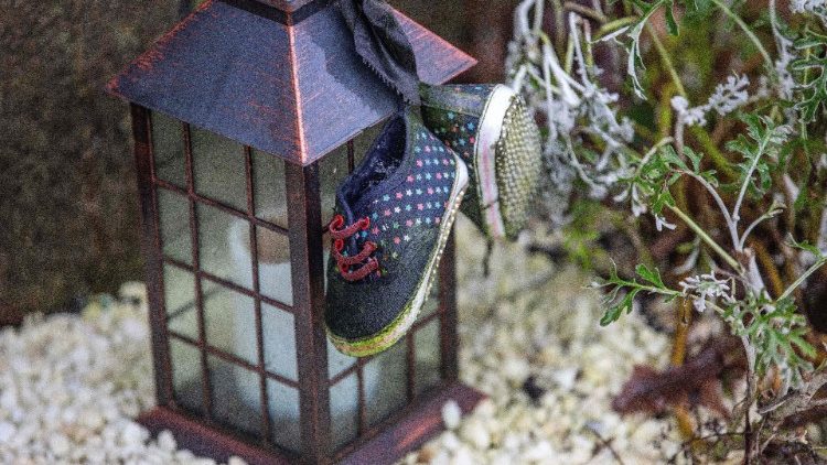 Calçado de crianças junto à luminária com vela em Tuam, Condado de Galway, recorda crianças vítimas de instituição religiosa