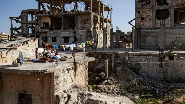 Children on the roof of a damaged building in Syria
