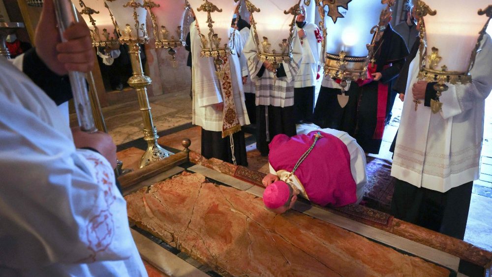 Bispo beija a Pedra da Unção, onde o corpo de Jesus Cristo foi depositado após ser retirado da Cruz, durante a Missa da Vigília Pascal no Sábado Santo, na Igreja do Santo Sepulcro em Jerusalém, em 3 de abril de 2021. (Foto de Emmanuel DUNAND / AFP)