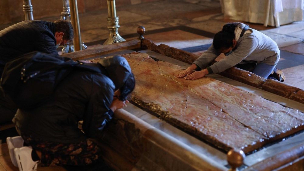 Fiéis rezam ajoelhados junto à Pedra da Unção, lugar onde o corpo de Jesus Cristo foi colocado após ser retirado da Cruz, durante a Nissa de Vigília Pascal no sábado Santo, na Igreja do Santo Sepulcro em Jerusalém