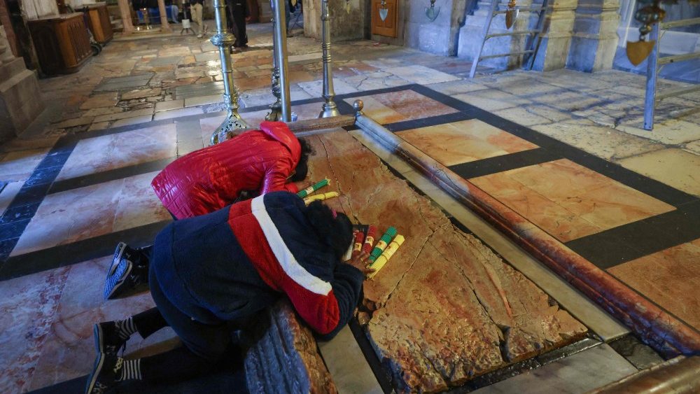 Fiéis rezam ajoelhados junto à Pedra da Unção, lugar onde o corpo de Jesus Cristo foi colocado após ser retirado da Cruz, durante a Nissa de Vigília Pascal no sábado Santo, na Igreja do Santo Sepulcro em Jerusalém