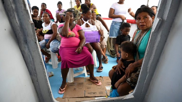 Auf diesem Dateifoto vom 24. April 2019 warten die kolumbianische Wounaan-Angehörige Yenny Cardena (rechts) und ihr Sohn zusammen mit afrikanischen Nachkommen auf eine Untersuchung im Krankenhausschiff "San Raffaele" in ihrer Gemeinde am Ufer des Flusses San Juan im Departement Choco, Kolumbien.