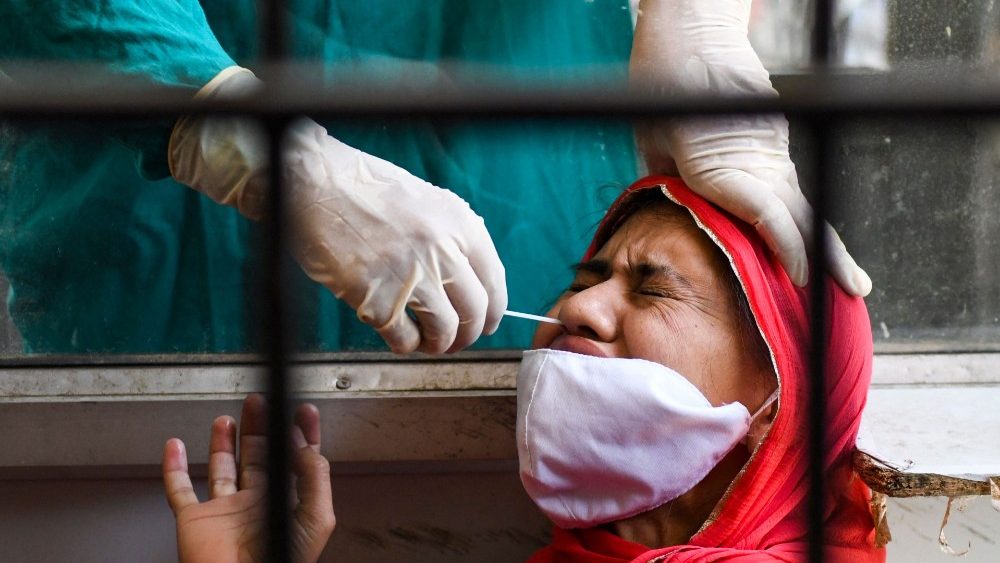 Profissional de saúde coleta amostra de esfregaço nasal de uma mulher para testar o coronavírus em Amritsar em 26 de abril de 2021. (Foto de Narinder NANU / AFP)