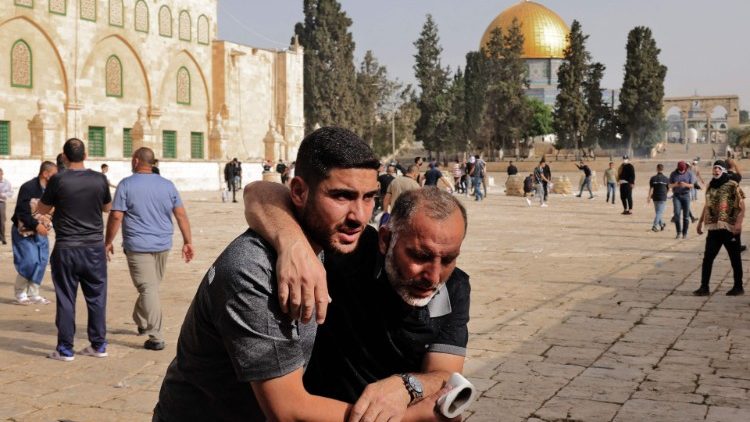 A Palestinian man helps a wounded protester