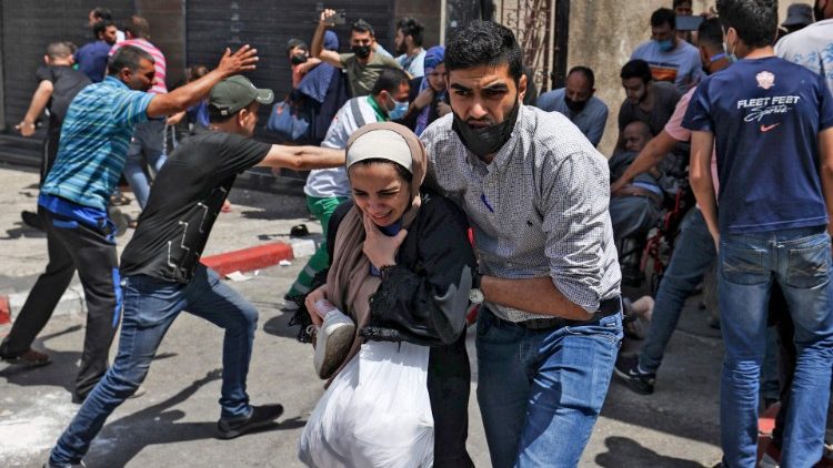 Palestinians evacuate a building targeted by Israeli bombardment in Gaza City on 11 May 2021