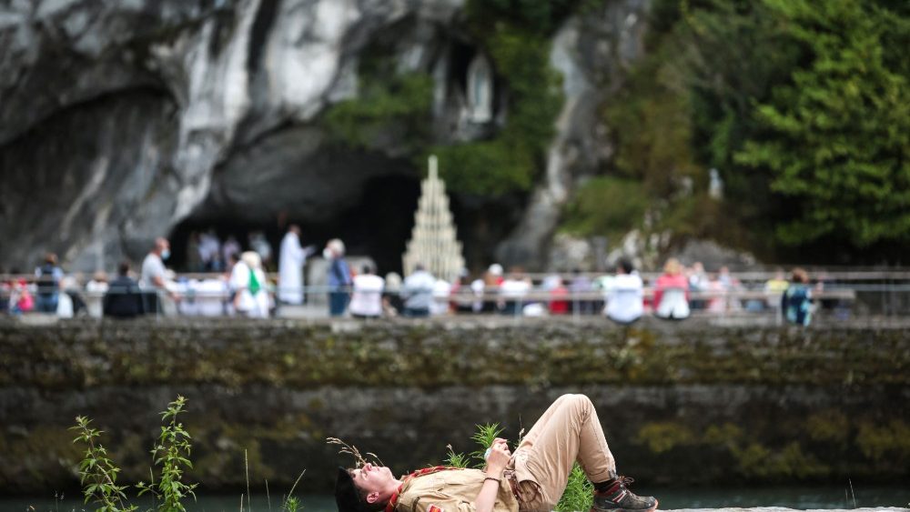 Escoteiro descansa em frente à Gruta de Massabielle, enquanto o Santuário católico de Notre Dame de Lourdes recebe os peregrinos após meses de fechamento devido à pandemia. (Photo by MATTHIEU RONDEL / AFP)