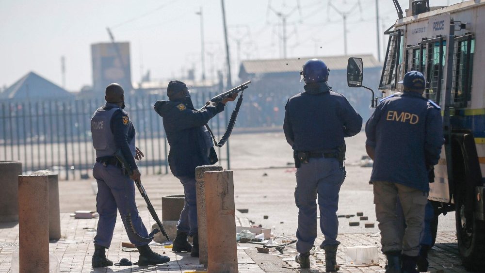 Membro dos Serviços de Polícia da África do Sul (SAPS) atira balas de borracha contra saqueadores após saques esporádicos e vandalismo do lado de fora do Lotsoho Mall, no município de Katlehong, a leste de Joanesburgo. (Photo by Phill Magakoe / AFP)
