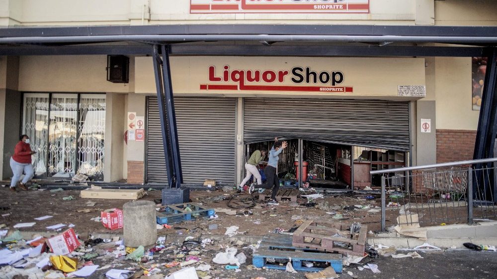 Manifestantes fogem de policiais após saquearem uma loja de bebidas no Jabulani Mall, no distrito de Soweto, em Joanesburgo.  (Photo by LUCA SOLA / AFP)