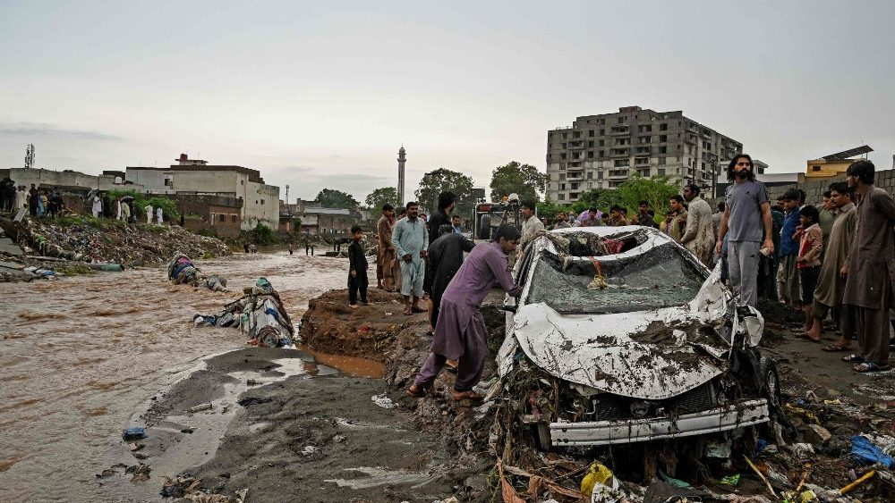 Moradores tentam remover um carro danificado preso na lama ao longo de uma rua inundada após fortes chuvas de monções em Islamabad em 28 de julho de 2021. (Foto de Aamir QURESHI / AFP)