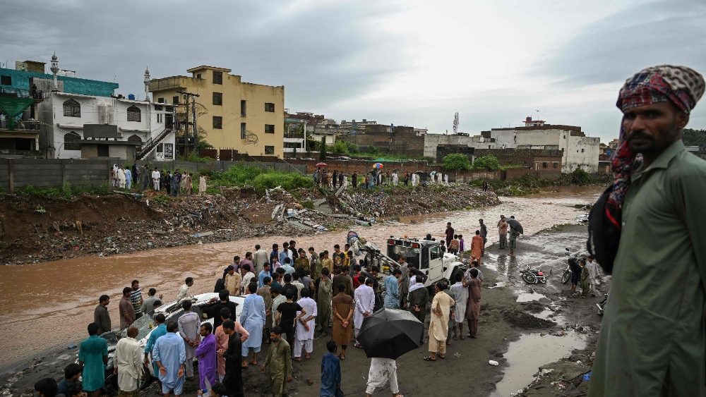 Moradores se reúnem próximo a uma rua que foi inundada após fortes chuvas de monções em Islamabad em 28 de julho de 2021. (Foto de Aamir QURESHI / AFP)