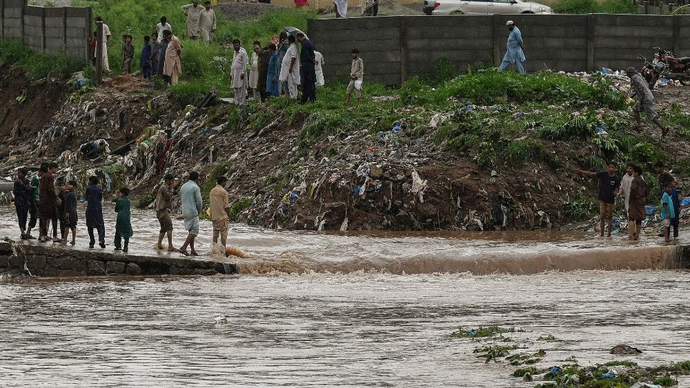 Moradores cruzam um riacho em uma estrada que foi inundada após fortes chuvas de monções em Islamabad em 28 de julho de 2021. (Foto de Aamir QURESHI / AFP)
