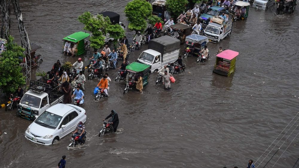 Motos e veículos seguem por uma rua inundada após fortes chuvas de monções em Lahore em 31 de julho de 2021. (Foto: Arif ALI / AFP)