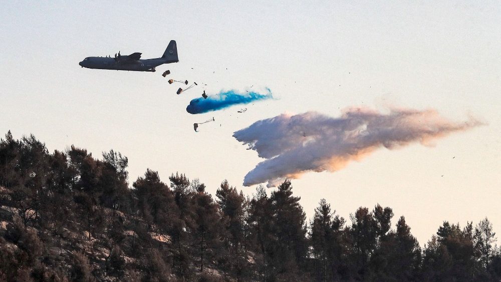 Uma aeronave Lockheed C-130 Hercules libera retardante de fogo ao tentar extinguir um incêndio florestal perto do Kibutz Tzova no centro de Israel a oeste de Jerusalém em 17 de agosto de 2021. (Foto de Ahmad GHARABLI / AFP)
