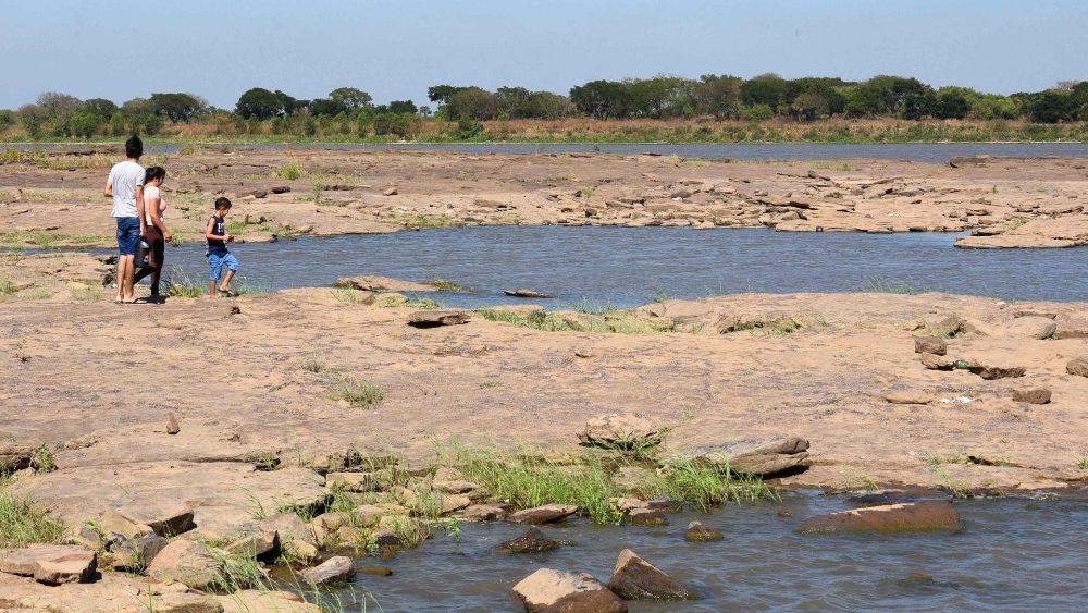 Moradores caminham sobre as pedras -geralmente cobertas pelo rio Paraguai- após a severa seca (AFP)