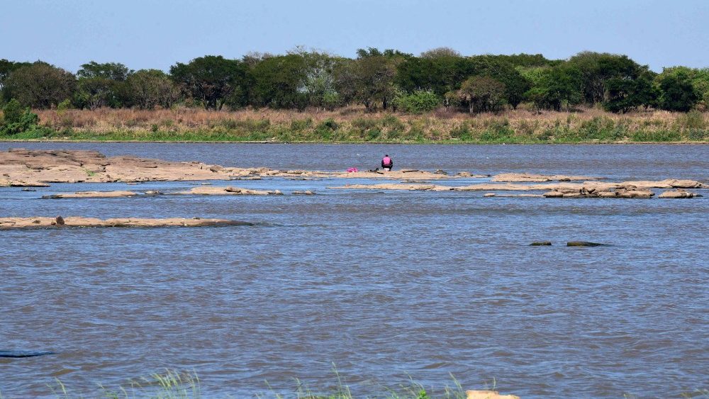 Um morador pesca sentado em pedras -geralmente cobertas pelo rio Paraguai- após a severa seca ((AFP)