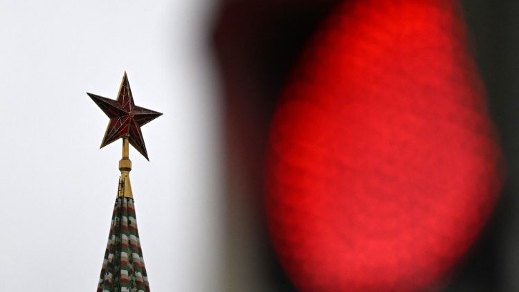 Vista de uma estrela de rubi no topo de uma das torres do Kremlin e o sinal vermelho de um semáforo no centro de Moscou em 24 de fevereiro de 2022 (Foto de Kirill KUDRYAVTSEV_