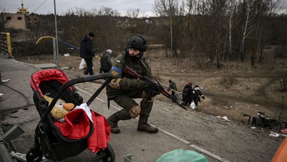 Un soldato ucraino accanto ai civili fuggiti da Irpin (Aris Messinis/Afp)