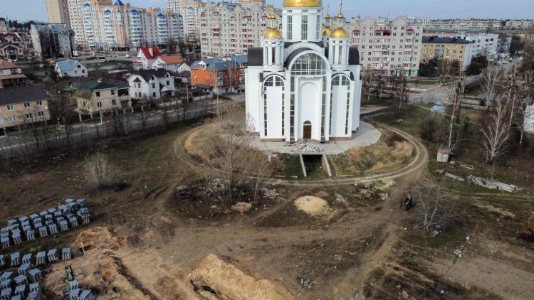 Uma vista aérea mostra sacos para corpos em uma trincheira (C, para baixo) de uma vala comum no jardim ao redor da igreja de Santo André em Bucha, em 7 de abril de 2022, em meio à invasão militar da Rússia lançada na Ucrânia. - O chefe humanitário da ONU disse em 7 de abril durante uma visita à cidade de Bucha, nos arredores da capital ucraniana, Kiev, que incluiu uma parada no local de uma vala comum que os ucranianos cavaram perto de uma igreja, que os investigadores investigariam as mortes de civis descobertas após As tropas russas se retiraram. (Foto de RONALDO SCHEMIDT/AFP)