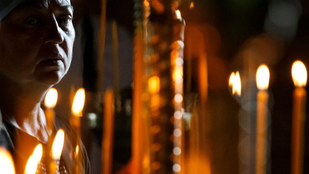 Uma mulher participa de um serviço religioso em uma igreja na cidade de Mariupol em 2 de junho de 2022, em meio à ação militar russa na Ucrânia. (Foto por STRINGER/AFP)