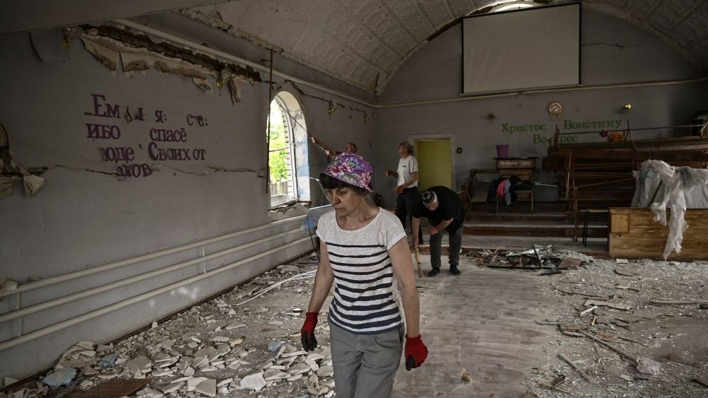 Uma mulher entra em uma igreja destruída após um ataque com mísseis, que matou uma idosa, na cidade de Druzhkivka (também escrito Druzhkovka) na região leste ucraniana de Donbas em 5 de junho de 2022. (Foto de ARIS MESSINIS / AFP)