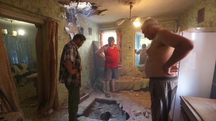 Moradores locais observam os restos de um míssil Smerch não detonado após um ataque noturno nos arredores de Kramatorsk, região de Donetsk, em julho de 2022, quando a guerra Rússia-Ucrânia entra em seu 152º dia. (Foto de Anatolii Stepanov/AFP)