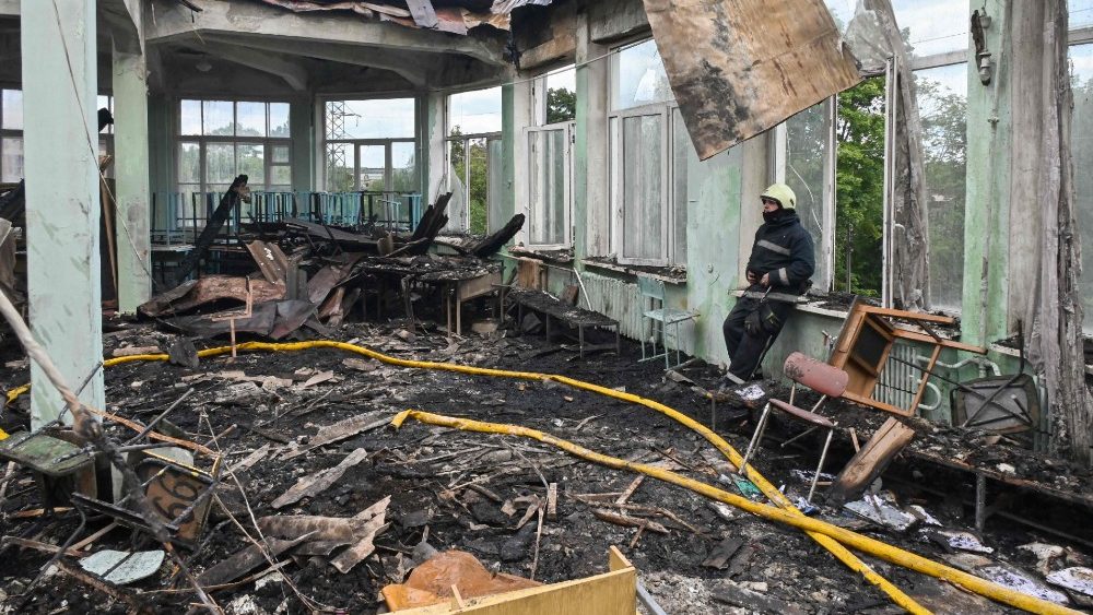 Bombeiro olha desolado escola vocacional destruída por míssil russo em Kharkiv, em 30 de julho de 2022. (Photo by Sergey Bobok/AFP)