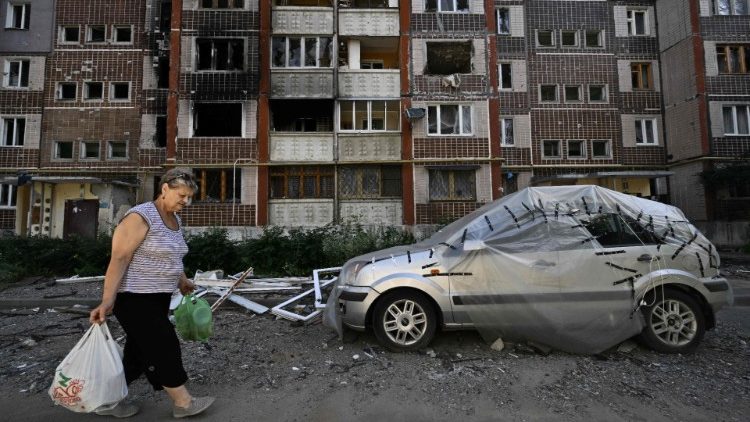 Moradora caminha diante de prédio atingido por foguetes russos em Saltivka, segunda maior cidade de Kharkiv. PHOTO by Genya Savilov/AFP