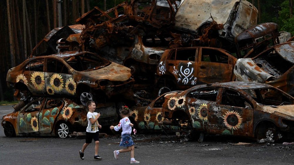 Crianças ucranianas brincam em cemitério de veículos destruídos por tropas russas em Irpin, e decorados por artistas (Photo by Sergei Supinsky)