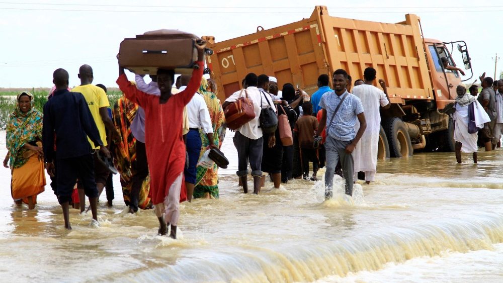 Sudaneses atravessam uma estrada inundada na cidade de Iboud, 250 km ao sul da capital Cartum, em 22 de agosto de 2022. (Foto de Ebrahim Hamid/AFP)