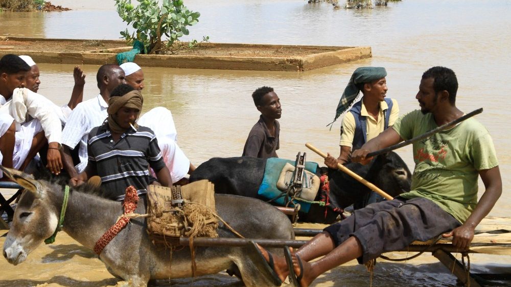 Sudaneses atravessam uma estrada inundada na cidade de Iboud, 250 km ao sul da capital Cartum, em 22 de agosto de 2022. (Foto de Ebrahim Hamid/AFP)