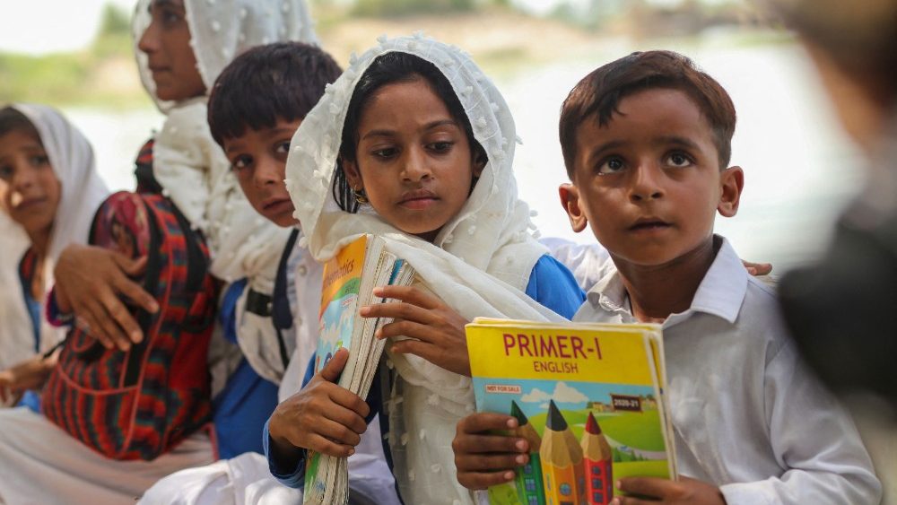 Crianças sentam em um barco quando voltam para casa depois da escola em uma área atingida por inundações após fortes chuvas de monção no distrito de Dera Ghazi Khan, na província de Punjab, em 29 de agosto de 2022. - O número de mortos por inundações de monções no Paquistão desde junho atingiu 1.136, segundo com números divulgados em 29 de agosto pela Autoridade Nacional de Gestão de Desastres do país. (Foto de Shahid Saeed MIRZA/AFP)