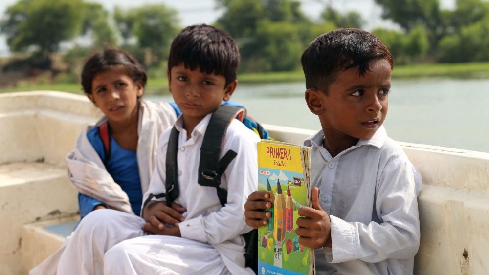 Crianças sentam em um barco quando voltam para casa depois da escola em uma área atingida por inundações após fortes chuvas de monção no distrito de Dera Ghazi Khan, na província de Punjab, em 29 de agosto de 2022. - O número de mortos por inundações de monções no Paquistão desde junho atingiu 1.136, segundo com números divulgados em 29 de agosto pela Autoridade Nacional de Gestão de Desastres do país. (Foto de Shahid Saeed MIRZA/AFP)
