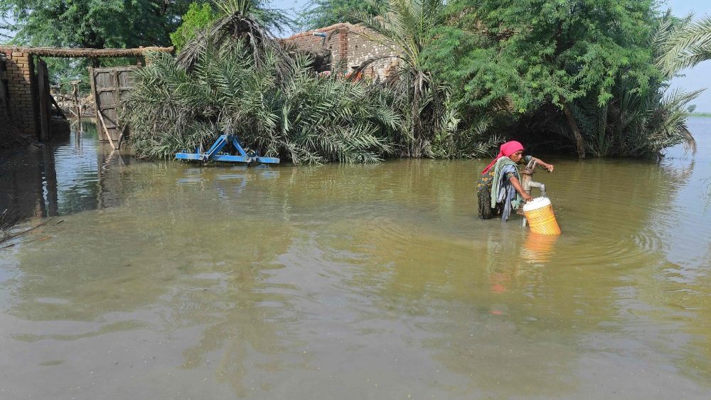 Uma mulher afetada por enchentes enche água potável de uma bomba manual parcialmente submersa perto de sua casa inundada em Shikarpur, na província de Sindh, em 30 de agosto de 2022. - Os esforços de ajuda aumentaram no Paquistão inundado em 30 de agosto para ajudar dezenas de milhões de pessoas afetadas pelas monções implacáveis chuvas que submergiram um terço do país e ceifaram mais de 1.100 vidas. (Foto de Asif HASSAN/AFP)
