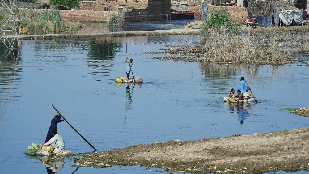 Pessoas usam balsas improvisadas para atravessar uma área inundada após chuvas de monção nos arredores de Sukkur, província de Sindh, em 1º de setembro de 2022. (Photo by Asif HASSAN / AFP)