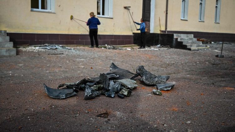 Trabalhadores limpam a fachada de um prédio escolar danificado após um ataque com mísseis em Kharkiv em 3 de setembro de 2022, em meio à invasão russa da Ucrânia. (Foto por SERGEY BOBOK/AFP)