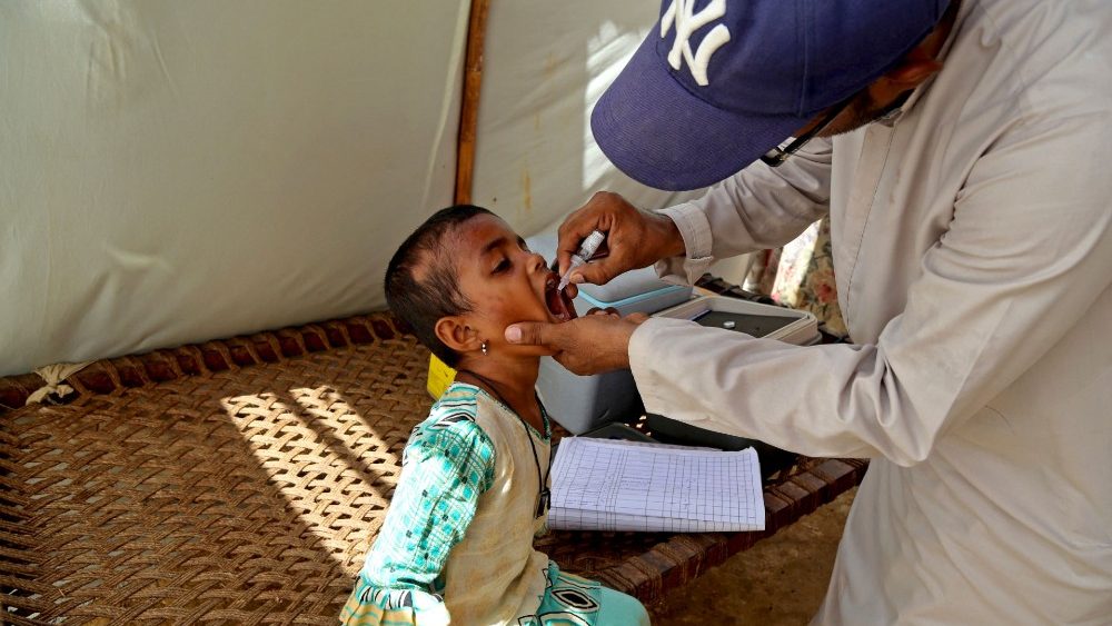 Um profissional de saúde administra gotas de vacina contra a poliomielite a uma criança dentro de uma tenda de deslocados internos afetados por enchentes em um acampamento na área atingida por fortes chuvas de monção em Hyderabad, província de Sindh, em 6 de setembro de 2022.. (Photo by Akram SHAHID / AFP)