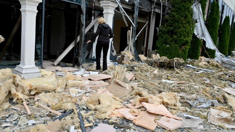 Uma mulher caminha pelos escombros do lado de fora do centro de entretenimento Misto (Cidade) parcialmente destruído como resultado de um ataque de míssil, em Kharkiv, em 11 de setembro de 2022, em meio à invasão russa da Ucrânia. (Foto de SERGEY BOBOK/AFP)