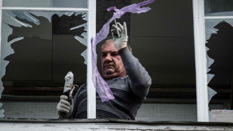 Um homem remove a janela quebrada em um prédio residencial atingido por um ataque de mísseis em Kharkiv em 21 de setembro de 2022, em meio à invasão russa da Ucrânia. (Foto de Yasuyoshi CHIBA/AFP)