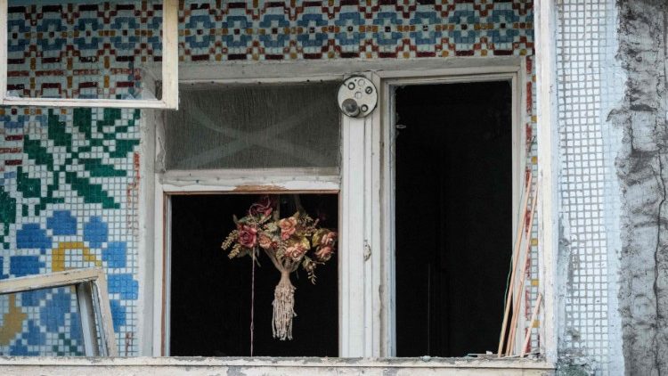 Flores secas são vistas em uma janela quebrada em um prédio residencial atingido por um míssil em Kharkiv em 21 de setembro de 2022, em meio à invasão russa da Ucrânia. (Foto de Yasuyoshi CHIBA/AFP)