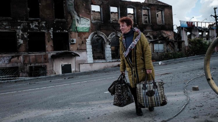 Uma mulher carregando pertences olha para trás depois de atravessar a ponte do rio Oskil enquanto fugia da cidade de Kupiansk, região de Kharkiv, em 24 de setembro de 2022, em meio à invasão russa da Ucrânia.