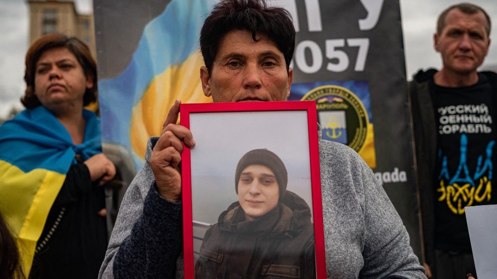 Uma mulher segura foto de seu filho durante uma manifestação exigindo acelerar a libertação da autoridade russa dos prisioneiros ucranianos envolvidos na batalha da usina siderúrgica Azovstal em Mariupol, no centro de Kiev, em 1º de outubro de 2022, em meio à invasão militar russa de Ucrânia. (Foto de Dimitar DILKOFF/AFP)