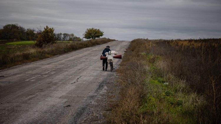 Uma idosa empurra sua bicicleta saindo da cidade de Bakhmut, na região de Donbas, no leste da Ucrânia, em 23 de outubro de 2022, em meio à invasão russa da Ucrânia. (Foto de Dimitar DILKOFF/AFP)