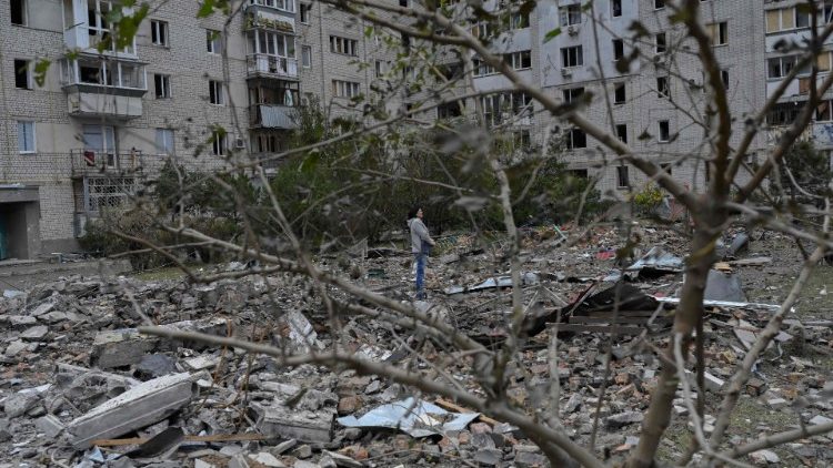Uma mulher fica no meio dos escombros após um ataque com foguete em Mykolaiv em 23 de outubro de 2022, em meio à invasão russa na Ucrânia. (Foto de BULENT KILIC/AFP)