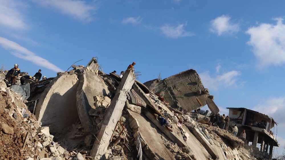 Sírios sobre os escombros de um prédio desabado, em 7 de fevereiro de 2023, na cidade de Jandaris, na parte controlada pelos rebeldes da província de Aleppo, enquanto uma operação de busca continua após um terremoto mortal. (Foto de Mohammed AL-RIFAI / AFP)
