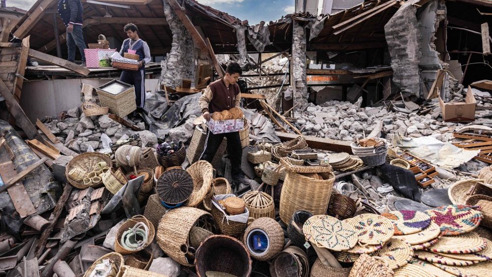 Mustafa Ozdimir ajuda sua família enquanto eles coletam mercadorias de sua loja destruída na cidade de Antakya em 19 de fevereiro de 2023. (Foto de Sameer Al-DOUMY / AFP)